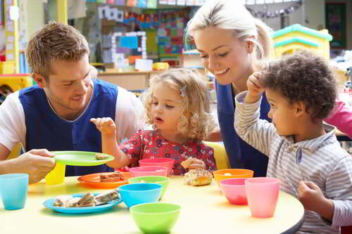 Kindergartenpädagogen bei einer gesunden Jause mit zwei Kindern